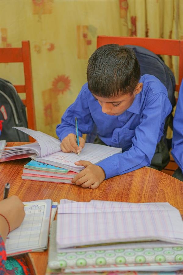 A student writing carefully in a notebook at a desk