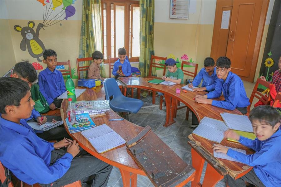 Students in blue uniforms working at curved desks in their classroom