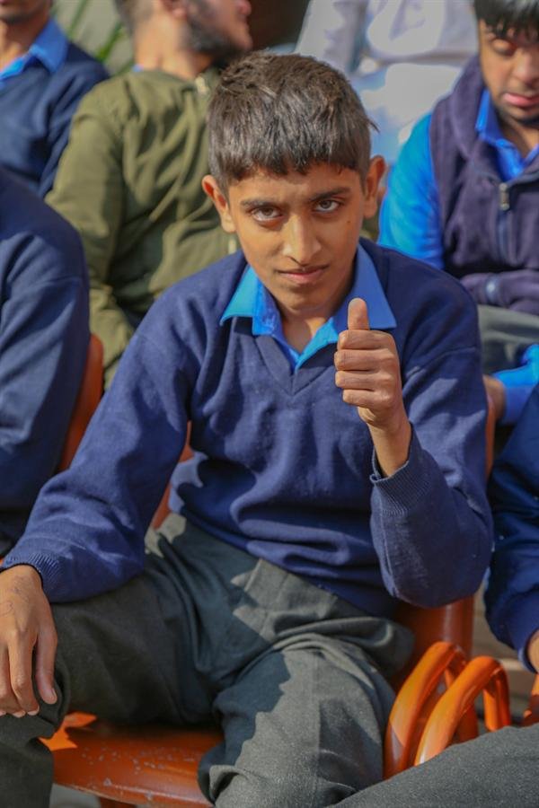 A student in a navy sweater giving a thumbs-up
