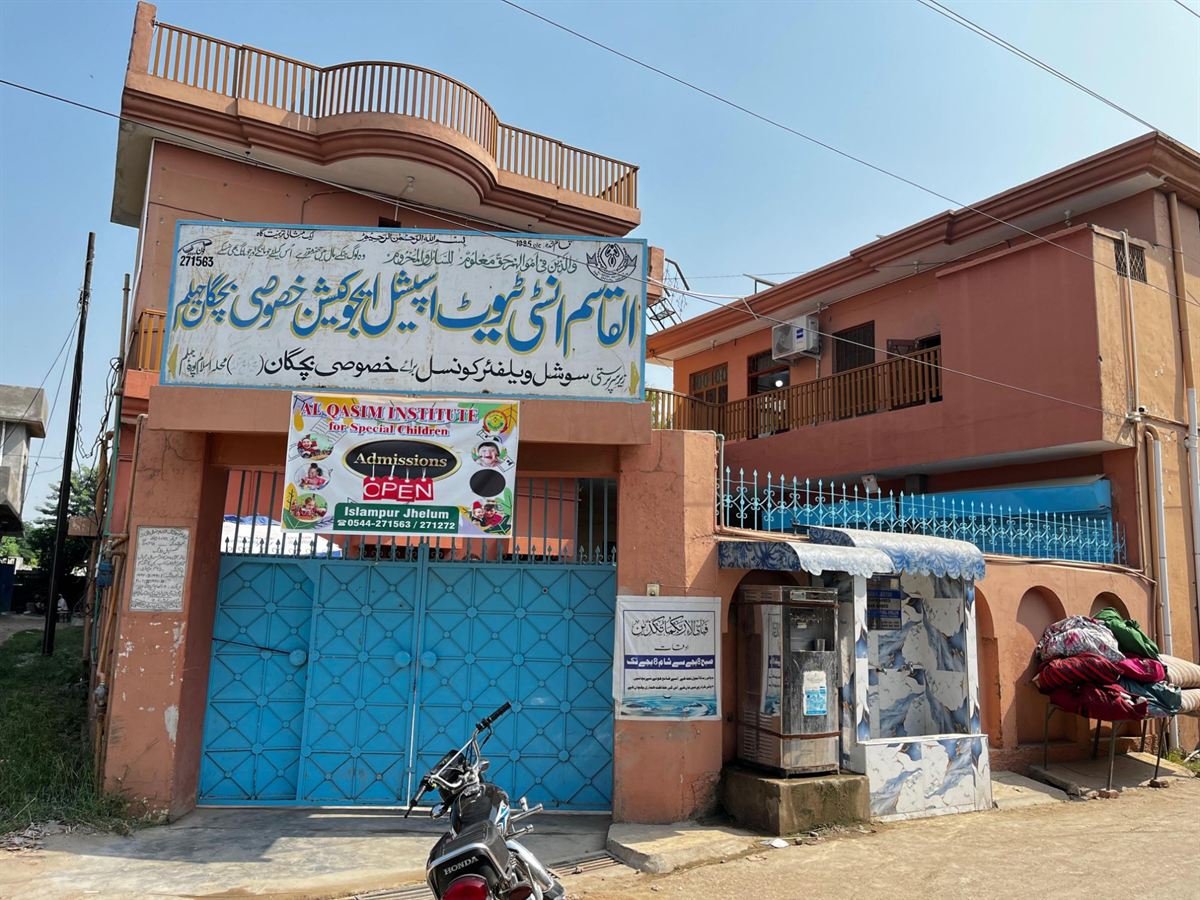 The Al Qasim Institute for Special Children building in Islampura, Jhelum, with its blue entrance gate and signboard